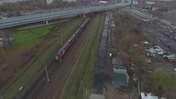 Vista aérea, tren rojo de dos pisos va a la velocidad en la ciudad en otoño — Vídeos de Stock