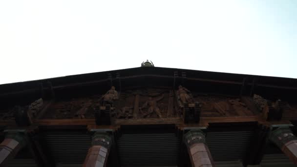 木造の屋根のある古い建物で建物の正面に彫像があります — ストック動画