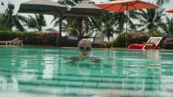 Jovem mulher em uma piscina azul-turquesa em óculos de sol — Fotografia de Stock