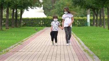Erkek ve kız kardeşler Coronavirus Covid 'in maskeleri ile yeşil sokağa giderler.