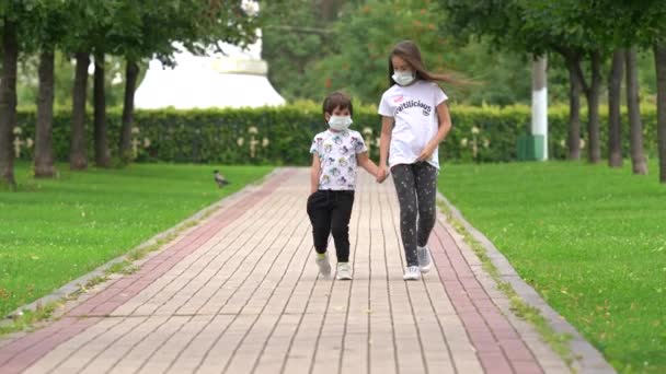 Brother and sister go at the green alley in medical masks from coronavirus covid — Stock Video