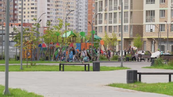 Дети играют на современной площадке в современном городе в солнечный день — стоковое видео