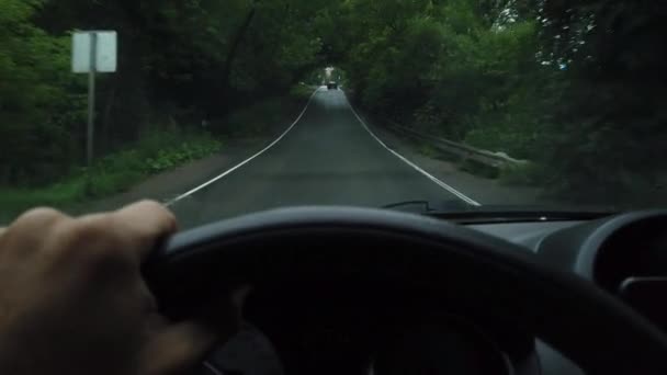 A mão de um homem dirige um carro ao longo de uma estreita estrada pavimentada na floresta. Fecha. Fipv... — Vídeo de Stock