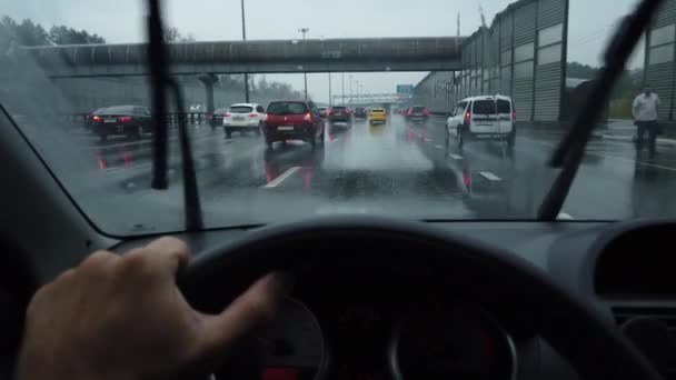 Мужская рука водит машину в дождливый день в интенсивном движении, вид от первого лица — стоковое видео
