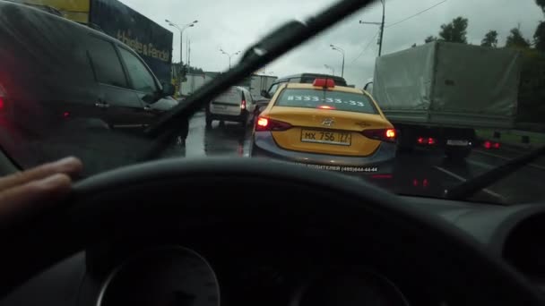 Мужская рука водит машину в дождливый день в интенсивном движении, вид от первого лица — стоковое видео