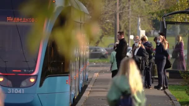 Passagers portant des masques protecteurs du coronavirus entrent dans le tram à un arrêt — Video