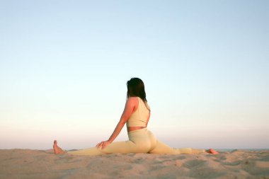 Gün batımında sahilde yoga yapan genç bir kadın. Akdeniz 'de egzersiz yapan bir kızın stok fotoğrafı..