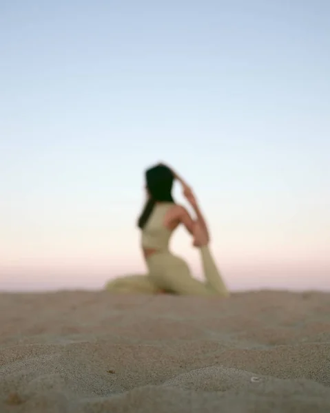 Gün batımında sahilde yoga yapan genç bir kadın. Akdeniz 'de egzersiz yapan bir kızın stok fotoğrafı..