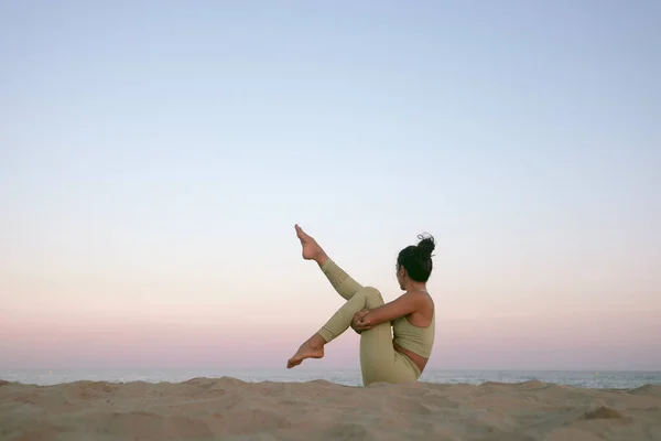 Gün batımında sahilde yoga yapan genç bir kadın. Akdeniz 'de egzersiz yapan bir kızın stok fotoğrafı..