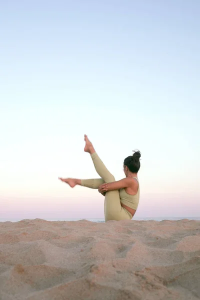 Gün batımında sahilde yoga yapan genç bir kadın. Akdeniz 'de egzersiz yapan bir kızın stok fotoğrafı..