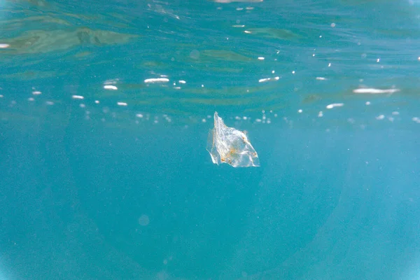 Plastic pollution floating in the sea underwater. Small micro plastics floating underwater in the ocean and polluting its marine life