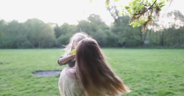 Jong gelukkig moeder en blond dochter genieten in het park en dansen — Stockvideo