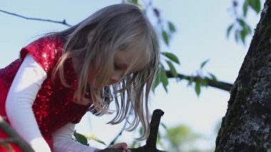 Yavaş hareket Kırmızı elbiseli mutlu sarışın küçük kız ağaca dokun