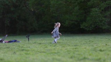 Küçük sarışın bir kız ağır çekimde gri, ağır çekimde koşuyor.