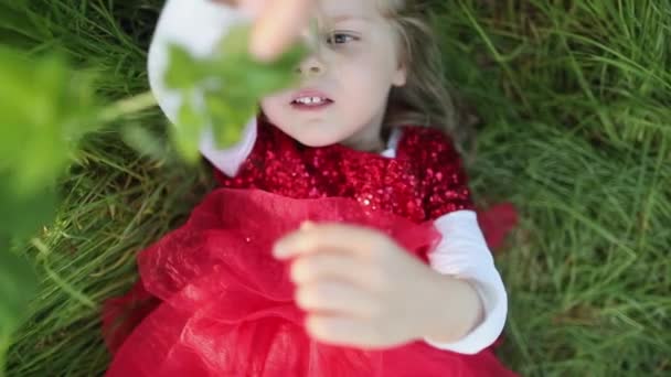 Menina feliz em vestido vermelho deitado no gras e dizer parar. Movimento lento . — Vídeo de Stock