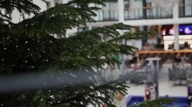 Alışveriş merkezindeki büyük süslü Noel ağacı ışıklarla yanıp sönüyor.