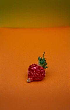 Turuncu arka planda tek kusurlu çilek