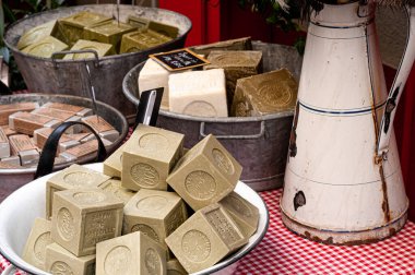 Süslü market tezgahında zeytinyağı sabunu. Su sürahisi ve kâseli Marsilya sabunu..