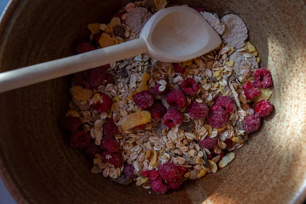 cereal bar ingredients in bowl with a wooden spoon . top view .