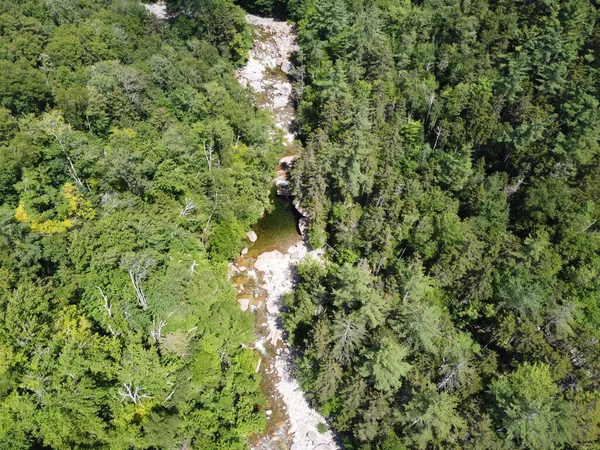 Drone aerial of hiking trail along river in New Hampshire mountains