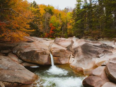 Kancamagus otoyolunun yakınındaki Franconia Falls 'un insansız hava aracı görüntüsü New Hampshire' da sonbaharda tam çiçekleniyor.