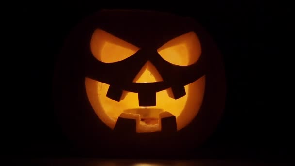Dýňová hlava na černém pozadí pro Halloween. Zlá tvář. Blikající svíčka. Místo pro text pozvání na dovolenou nebo oslavu, noční večírek, horor. — Stock video