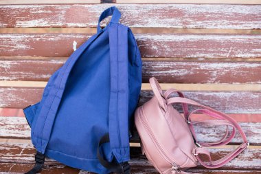 bir çift, erkek ve zaman bir yürüyüş sonra dinlendirici bir kadın, küçük ve büyük, parkta, eski ahşap bankta iki modern kentsel sırt çantaları. 