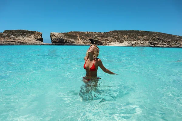 Bela mulher modelo sexy em biquíni vermelho relaxante em lagoa azul, de pé em água azul sorrindo, desfrutando de férias e viajando — Fotografia de Stock