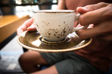 bir fincan genç yakışıklı adam sıcak cappuccino, rahatlatıcı, içme ve arkadaşlar ile bir kafede oturuyor bir yakın çekim