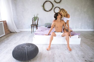 modern çatı bedrooom, aşk kavramı sabah yatak sarılma üzerinde oturan genç güzel bir çift