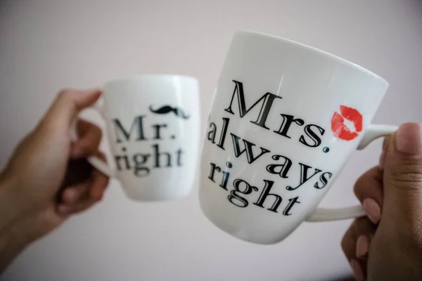 Una giovane coppia che porta tazze bianche di tè o caffè con le parole Mr right e Mrs sempre ragione Fotografia Stock