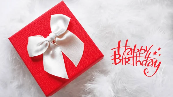 Primo piano di una bella confezione regalo bianca e rossa per il regalo di compleanno, in piume bianche — Foto Stock