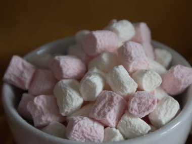 kahverengi bir arka plan üzerinde beyaz bir fincan küçük mini marshmallows yakın