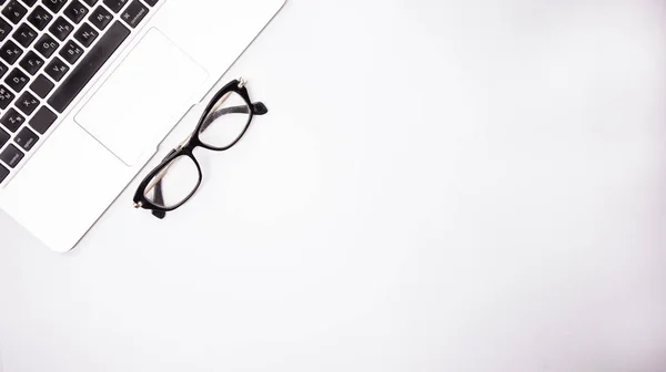 Szary laptop z czarnymi okularami na białym tle tabeli, miejsce pracy w domu lub w biurze Zdjęcia Stockowe bez tantiem