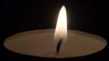 Küçük mumlar yanıyor. Ağır çekimde yaklaşın. Karanlıkta mum alevleri..