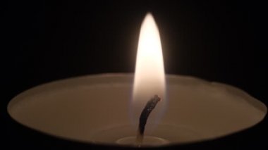 Küçük mumlar yanıyor. Ağır çekimde yaklaşın. Karanlıkta mum alevleri..