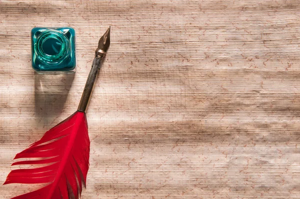 红羽毛笔和一张木桌上的纸莎草纸表 — 图库照片