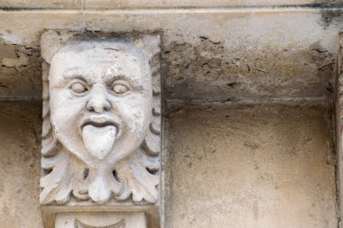 Closeup view of mascarons with a funny face under the balcony of a baroque palace in the province of Syracuse, Sicily clipart