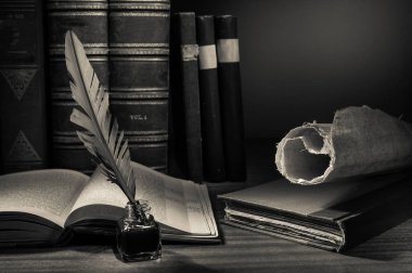 Quill'in kalem ve eski kitaplar ile ahşap bir masa üzerinde açık bir kitap