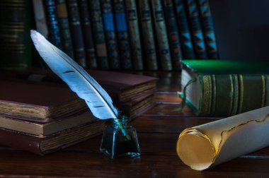 Quill'in kalem ve eski kitaplar ile ahşap bir masa bir haddelenmiş papirüs sayfada