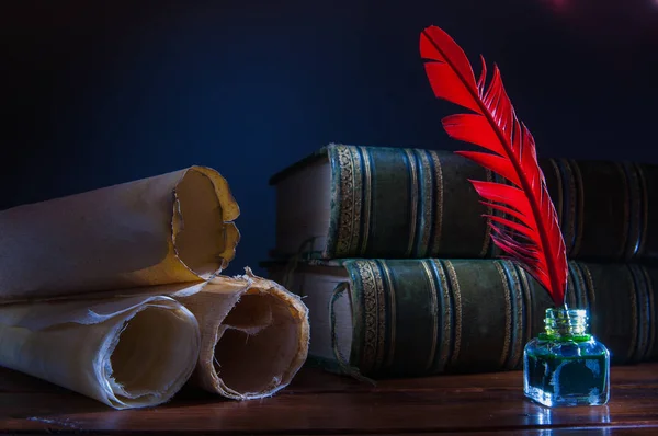 赤い羽根ペンと古書の木製テーブルの上圧延パピルス シート — ストック写真