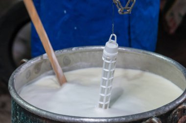 Çiftçi süt kazanın içinde çalışıp tuma peyniri yapıyor.