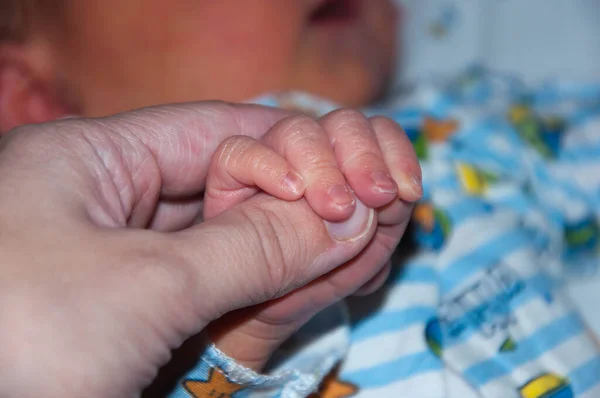 Babacan bir elde bir erkek bebek. Bebek ağzında bir emzikle uyuyor..