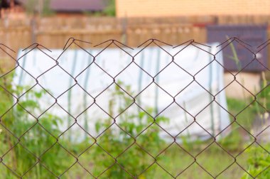 Bahçede yeşil arka planı olan çelik çitler..