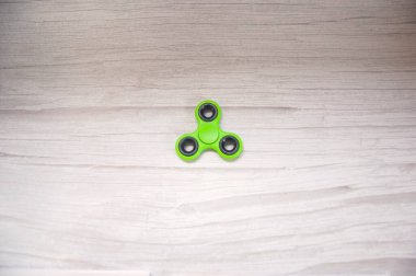 Gri ahşap masada yeşil hareketli dönen alet izole edildi. Arkaplan