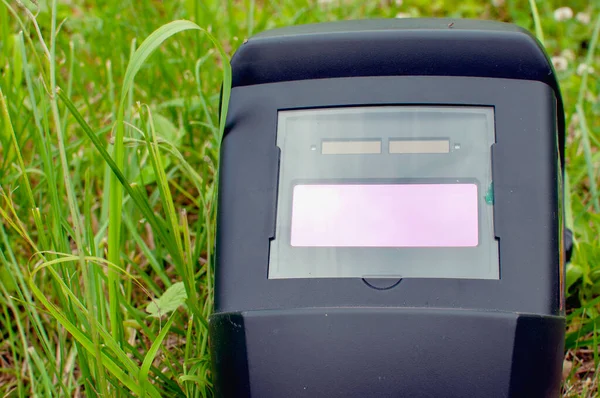 Çimlerin üzerinde kaynak ve güvenlik gözlükleri için koruyucu bir maske var. Makroyu kapat