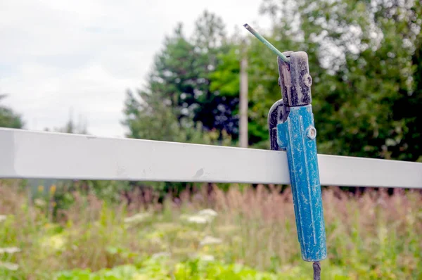 Çitin üzerinde eski bir kaynak aleti var. Bahçedeki eski ve paslı kaynak makinesi. Makroyu kapat