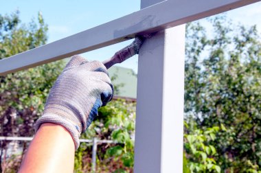 Çitlere paslı sopa boyama işlemi. Adam çitle fırça boyuyor. Makroyu kapat