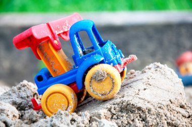 Çocukların oyuncak arabası, kumdaki renkli plastik kamyon. Yakın plan. Seçici odaklanma. Boşluğu kopyala