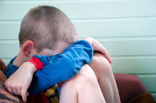 Koltukta oturan korkmuş bir gencin çocuk istismarı kompozisyonu. Kapat.